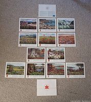 All 12 prints arranged on carpet with inner sleeve and red envelope with Centennial crest visible