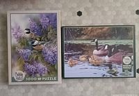 Two Cobble Hill bird puzzles, "Chickadees and Lilacs" and "Platts Pond (Geese and Goslings)", each 1000 pieces, box front showing designs.