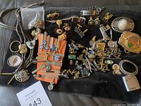Full lot overview showing all assorted men's accessories laid out on black background including bolo ties, tie clips, cufflinks, pins, belt buckles, and lighter.