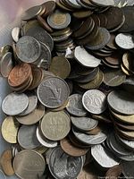 Coins in a container showing a variety of metal types, denominations, and designs from several countries.