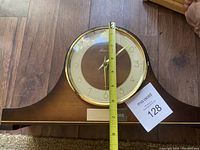 Front view of German wooden table clock with glass dome face and measuring tape showing approximately 7.5 inches tall.