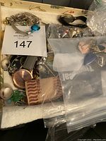 Large tote filled with assorted jewelry and wristwatch with rose gold face.