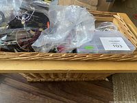 Basket containing multiple plastic containers and bags filled with various jewelry making components including beads and clasps.