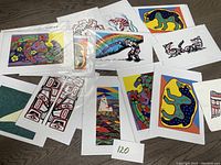 Overview of multiple Native First Nations art cards spread on a table showing various animal and traditional motifs in vibrant colors, most sealed with envelopes