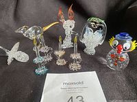 Photo showing the full lot from front: spun glass bird, rabbit, kangaroo, swan figures in basket, candlesticks, and Murano clown.