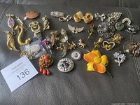Wide shot showing assortment of jewelry pins in various styles and colors laid out on a dark surface