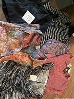 Lot of plus size women's clothing items, various shirts and knits laid out on floor, new with tags visible
