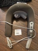 Front view of beige U-shaped plug-in neck massager with white control panel and attached power cord.