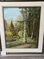 Full view of the painting showing the forest path alongside the lake with birch trees and surrounding nature, framed in wood.