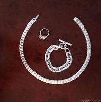 Ring, bracelet, and necklace laid out on a dark surface.