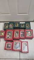 13 Waterford collectible Christmas ornaments displayed in original boxes on the floor, arranged in three rows with green and red packaging.