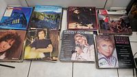 Photo of several album covers laid out, showing artists such as Kenny Rogers and Barbara Mandrell, with minor surface scratches on the covers visible.