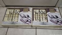 Two boxed Lenox Chandelle flatware sets side by side