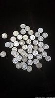 Scattered view of multiple silver quarters on black background