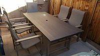 Full set: rectangular table with five sling chairs on concrete patio against cedar fence