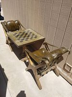 Wide angle photo showing chess table and two leather chairs on either side