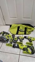 Full set of Ryobi ONE+ cordless power tools including circular saw, drill/driver, impact driver, reciprocating saw, battery, and carrying bag arranged on floor.