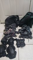 Photo shows two pairs of inline rollerblades, one Salomon and one Coolblade, with accompanying protective gear consisting of wrist guards, elbow pads, and knee pads, all arranged on a tiled floor.