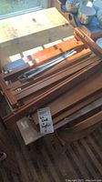 Folded wooden desktop easel parts stacked together showing the frame and metal supports.