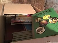 Open box showing partially visible books including Junior World Encyclopedia and educational titles