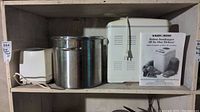 Shelf with Black & Decker white two-slice toaster, stainless steel canning pot, and boxed bread maker with instructions