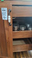 Photo of wooden cabinet door showing metal canisters with clear lids stored inside cabinet shelves.