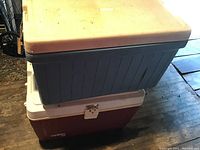 Side view showing a blue cooler with a beige lid stacked on top of a red cooler.