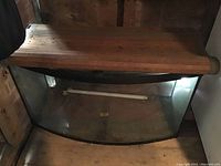 Full front view of the fish tank showing the wooden top lid and curved glass front.