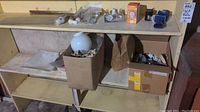 Wooden shelf holding boxes and loose items including light bulbs and lighting parts.