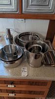 Collection of metal bowls, ice buckets, drink mixer, and food grater on counter