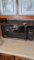 General Electric Space Maker II microwave positioned under kitchen cabinets on a countertop, showing its front side and door.