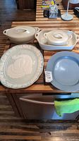 Lot of two covered Corning Ware casserole dishes, decorative turkey platter and blue plate on kitchen counter