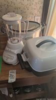 Photo shows white Hamilton Beach blender with clear glass pitcher, Sunbeam electronic skillet with lid and handle, and Hamilton Beach slow cooker with glass lid on wooden counter.