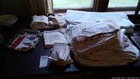 Wide view of sorted and folded table linens including a large tablecloth, napkins, and apron laid on a table