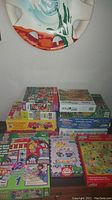 Lot of 11 children's puzzles stacked with visible colorful packaging and various cartoon themes.