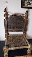 Front view of the 19th century SWAT Valley wooden chair showing carved wood backrest and woven seat.
