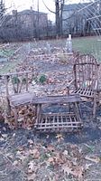 Full view of the bent willow furniture set consisting of two chairs and one bench placed outdoors on the ground with leaves.