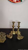 Photo showing two brass candlesticks and two mid-century bird-shaped brass bookends.