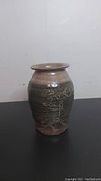 Front view of the handcrafted ceramic vase showing incised jack pine tree designs and glaze colors.