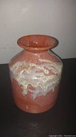 Front view of handmade glazed crock showing reddish base and white glaze drip pattern