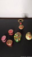 Group photo showing five handmade Kashmir paper mache trinket boxes and one candlestick with detailed floral paintings