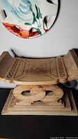 Front view of the large carved wooden Asante stool showing intricate geometric carvings and curved support base.