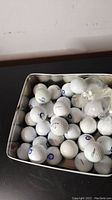 Tin filled with used golf balls showing various brands including Titleist, Dunlop, and Callaway