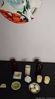 Several onyx items and two Japanese glass candlesticks arranged on surface, some onyx containers and ashtray with visible chips.