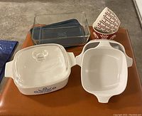 Top view showing all six items: Pyrex glass dish with lid, blue cornflower Corningware dish with lid, two small white Corningware dishes without lids, and two small red and white patterned bowls.