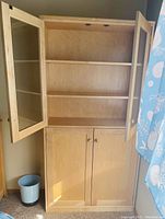 Front view of the solid maple curio cabinet with both upper glass doors open and the lower solid doors closed. Shows interior shelves and light wood finish.