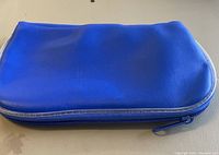 Blue leather-like zippered carrying case closed, showing outer appearance and zipper.