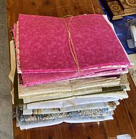 Stacked fabric bundles tied with twine showing different colors and patterns including pinks, browns, greys