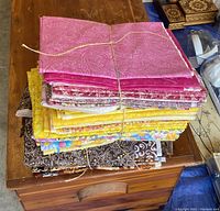 Bundles of folded quilting cotton fabric, various colors and patterns on a wooden surface