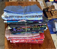 Top view of three bundles of folded quilting fabric in various colors and patterns including blue geometric and multicolored designs
